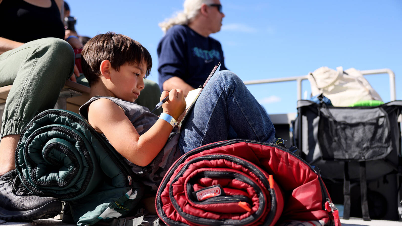 <p>Rye Galindo draws in a book about dinosaurs while on his first boat trip.</p>